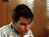 a man in a plaid shirt has his eyes closed