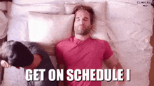 a man in a pink shirt is laying on a bed next to another man and the words get on schedule i