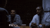 two men sitting at a table with the words " it 's when a " on the bottom