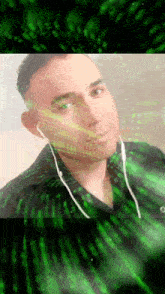 a man wearing ear buds looks at the camera with a green background behind him