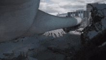 a large pipe is laying on the ground in front of a building with a cloudy sky in the background