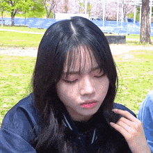 a girl with long black hair is making a funny face in a park