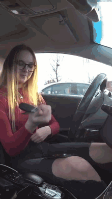 a woman wearing glasses is sitting in a car holding a lighter