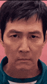 a close up of a man 's face with a pink background and a blue shirt .
