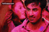 a man in a pink shirt is standing in a crowd with a woman in a pink shirt behind him .