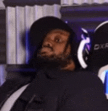a man with a beard is wearing headphones and a hat while sitting in front of a computer .