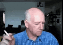 a bald man smoking a cigarette in a blue shirt