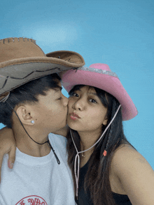 a man and woman wearing cowboy hats are kissing