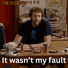 a man sits at a desk with a sign that says " the it crowd "