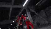 a red power ranger is fighting another power ranger with a sword in a dark room .
