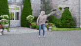 a woman is dancing in front of a large stone building in a driveway .