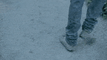 a man in a dirty sweater is walking down a dirt road .