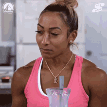 a woman wearing a pink tank top and a necklace with a lv pendant