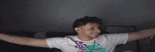 a man with his arms outstretched is wearing a t-shirt with a purple dinosaur on it