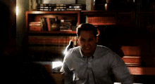 a man in a blue shirt is sitting in a chair in a living room with his arms outstretched .