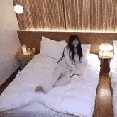 a woman is laying on a bed in a hotel room with a white blanket .