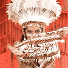 a woman is wearing a feathered headdress and a feathered costume