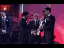 a man in a tuxedo shakes hands with another man in a suit