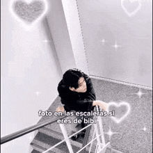 a man is standing on top of a set of stairs with hearts surrounding him .