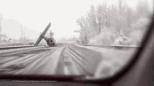 a car is driving down a snowy road with a broken propeller on the side of the road .