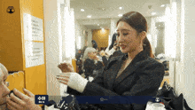 a woman in a suit is talking to another woman in a room with a sign that says su a