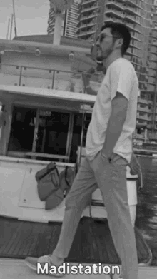 a black and white photo of a man standing in front of a boat with madistation written on the bottom