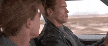 a man and a woman are sitting in a car and looking out the window .