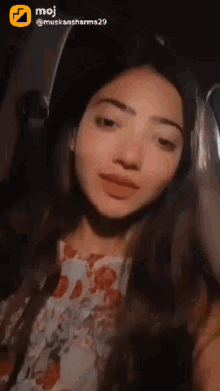 a woman is taking a selfie in a car with a moji logo in the corner