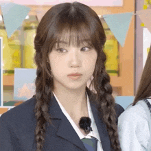 a girl with braids in her hair is wearing a school uniform and making a funny face .