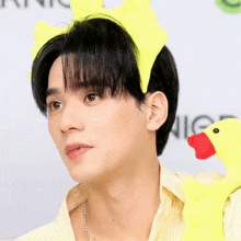 a man wearing a yellow headband and holding a stuffed duck