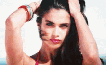 a woman in a red bikini has her hands in her hair