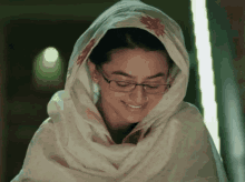 a woman wearing glasses and a scarf on her head smiles