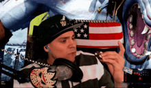 a man wearing headphones and a hat with the letter w on it is holding an american flag