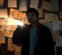 a man is holding a flashlight in front of a wall with drawings on it