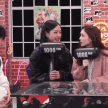 two women are sitting at a table with a microphone and a hammer .