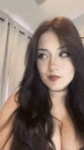 a woman with long dark hair and a choker around her neck is looking at the camera .