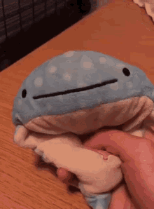 a person is holding a stuffed whale with a smiling face .