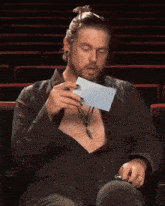 a man is sitting in a theater holding a piece of paper