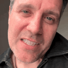 a man with a beard and a black jacket is smiling for the camera