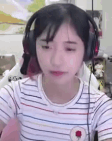 a girl wearing headphones and a striped shirt is sitting in front of a computer screen .