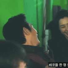 a man and a woman are laughing in front of a green screen .