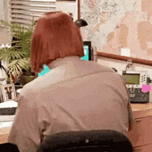a woman is sitting at a desk with a telephone and a computer .