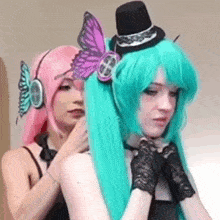 a woman in a pink wig is standing next to a woman in a green wig .