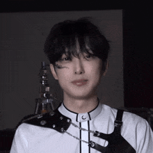 a close up of a person wearing a white shirt with black straps