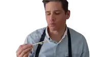 a man wearing a blue shirt and suspenders looks down at something