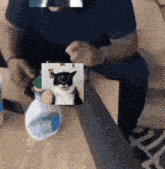 a man sitting on a couch holding a picture of a cat