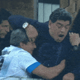 a man wearing a shirt that says maradona is being held by another man