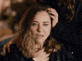 a woman with a ring on her finger holds her hand to her forehead