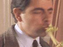a man in a suit and tie is smelling celery .
