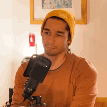 a man wearing a yellow beanie is sitting in front of a microphone that has the word nc on it